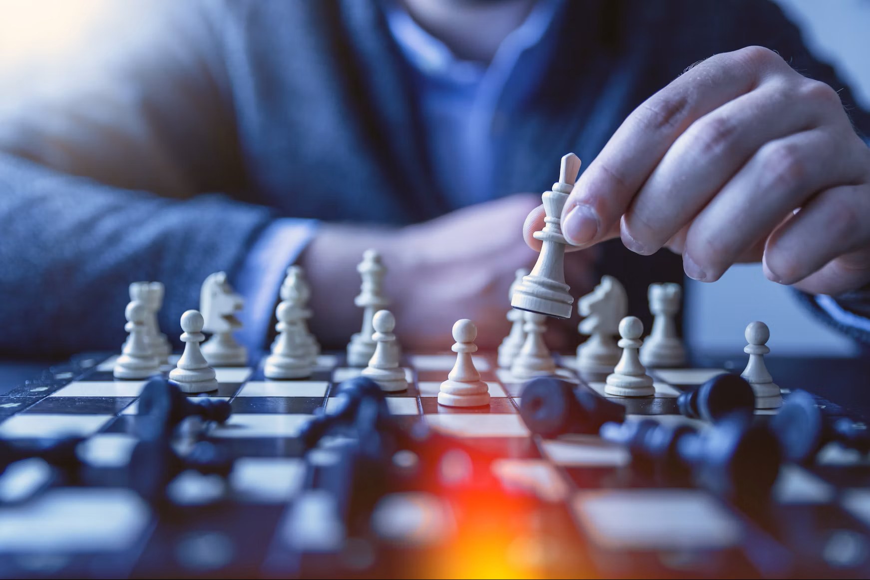 Hands moving a piece in the middle of a chess game